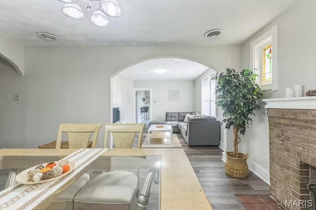 4931 Mardel Ave, Saint Louis, MO 63109 - dining space featuring arched walkways, wood finished floors, a fireplace with flush hearth, and baseboards
