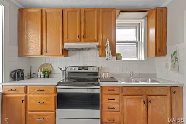 4931 Mardel Ave, Saint Louis, MO 63109 - kitchen with stainless steel range with electric stovetop, under cabinet range hood, a sink, light countertops, and tasteful backsplash