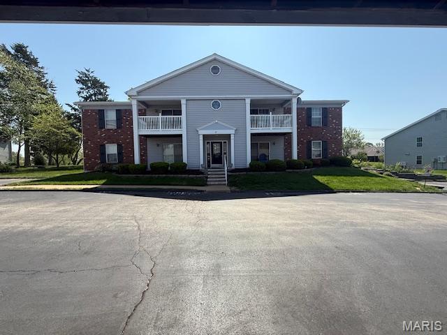 31 Berview Cir Unit H, Saint Louis, MO 63129 - neoclassical home featuring a balcony, a front lawn, and brick siding