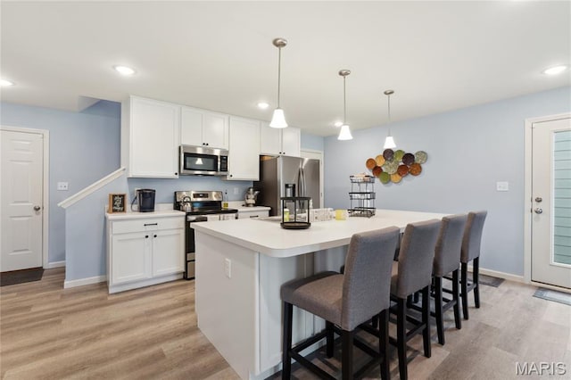 104 Tiber Way, Saint Charles, MO 63301 - kitchen with stainless steel appliances, a center island, light wood-style flooring, white cabinets, and a breakfast bar area