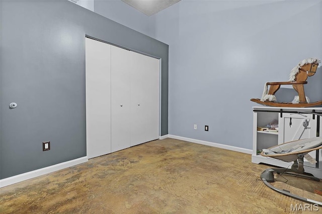 unfurnished bedroom featuring concrete flooring, baseboards, and a closet