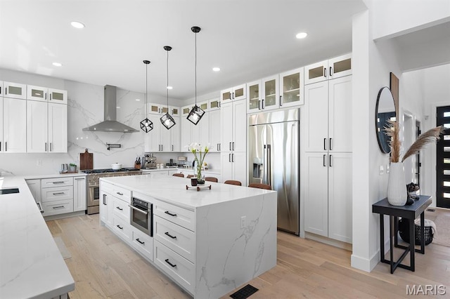 10010 Schuessler Rd, Saint Louis, MO 63128 - kitchen with high quality appliances, wall chimney range hood, a kitchen island, light wood-style flooring, and recessed lighting
