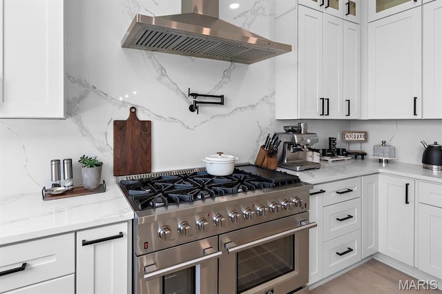 10010 Schuessler Rd, Saint Louis, MO 63128 - kitchen featuring range with two ovens, wall chimney exhaust hood, glass insert cabinets, and white cabinetry
