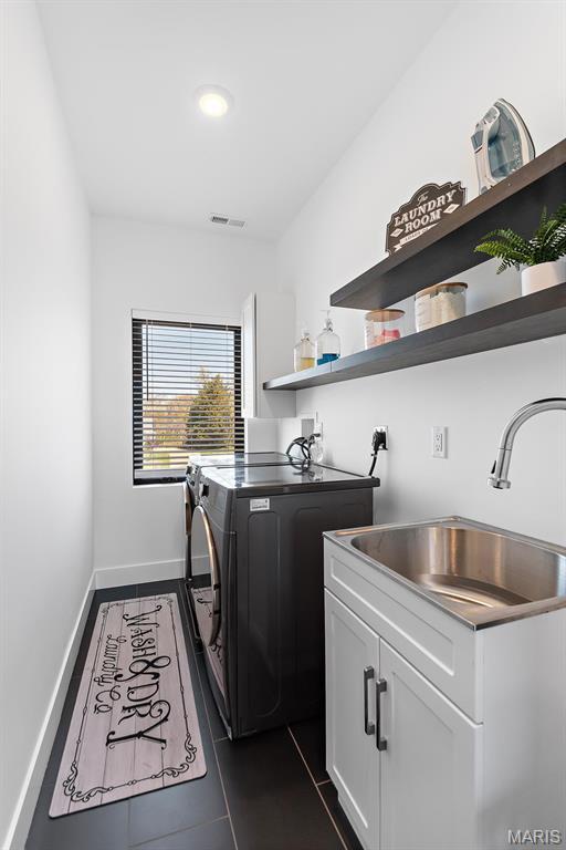 10010 Schuessler Rd, Saint Louis, MO 63128 - laundry area with washer and clothes dryer, cabinet space, baseboards, and dark tile patterned floors