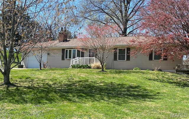 view of front of property featuring a chimney, a garage, and a front lawn