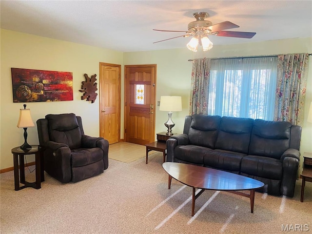 living area with light colored carpet, ceiling fan, and baseboards