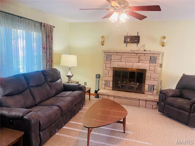 living area featuring ceiling fan, carpet flooring, and a fireplace