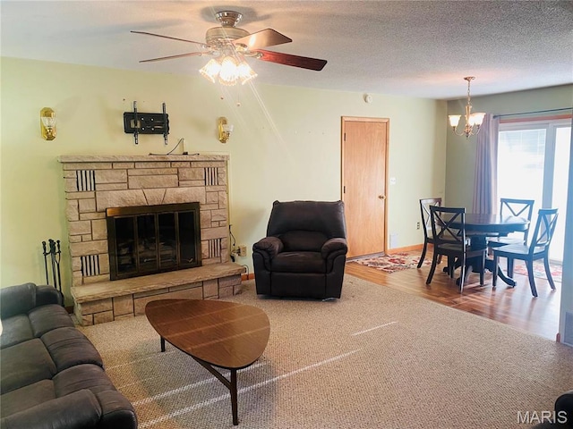 living room with a ceiling fan, carpet flooring, a stone fireplace, wood finished floors, and baseboards