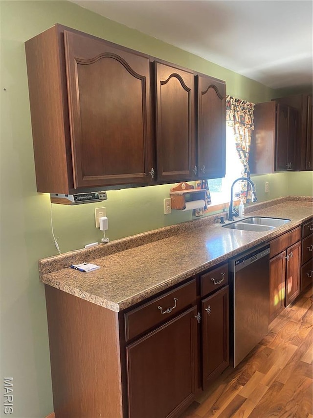 kitchen featuring stainless steel dishwasher, a sink, light wood-type flooring, and dark brown cabinets
