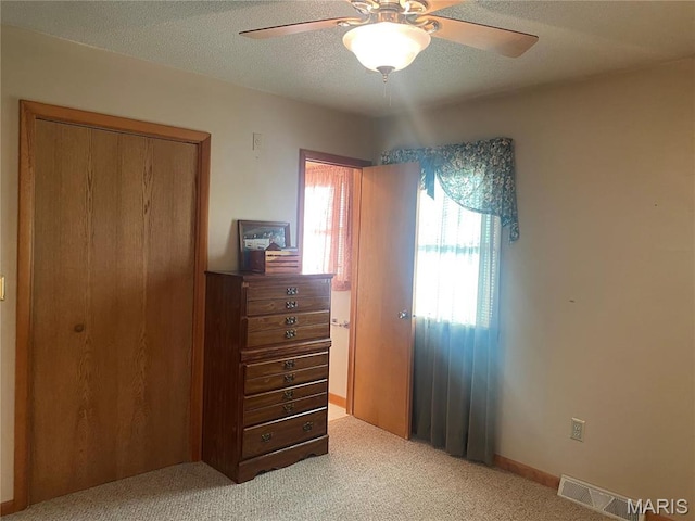 carpeted bedroom with ceiling fan, a textured ceiling, and a closet