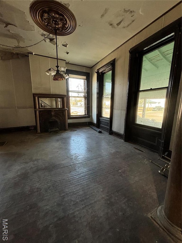 unfurnished living room featuring a chandelier and concrete flooring