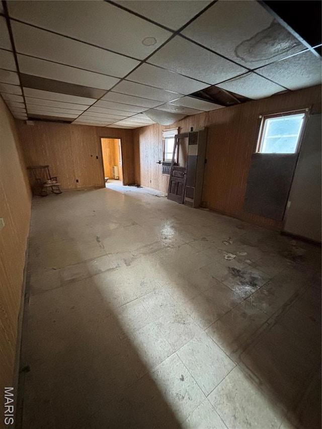 below grade area with wood walls, a paneled ceiling, and tile patterned floors