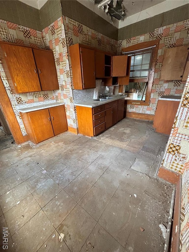 kitchen with brown cabinetry, light countertops, a sink, and a high ceiling