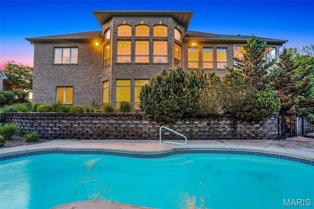 back of house with brick siding and an outdoor pool