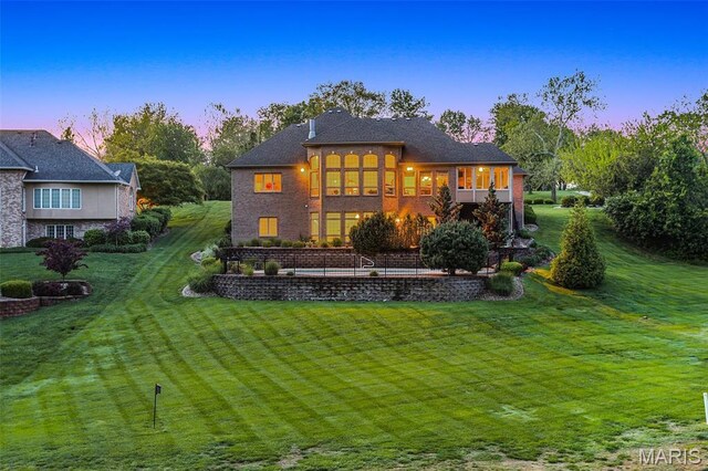 back of house at dusk with a sunroom and a yard