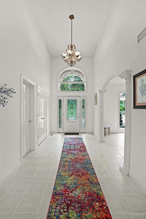 entryway with ornate columns, light tile patterned floors, arched walkways, a high ceiling, and crown molding