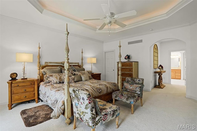 bedroom with arched walkways, a tray ceiling, carpet floors, crown molding, and baseboards
