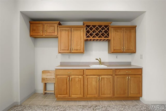 kitchen featuring a sink, brown cabinetry, light countertops, and light tile patterned floors
