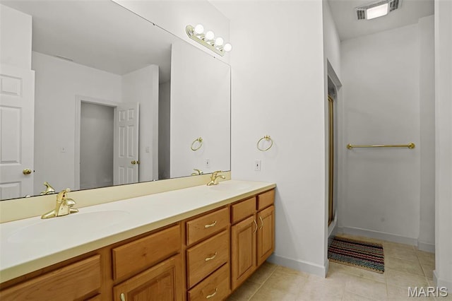 bathroom featuring tile patterned flooring, double vanity, a shower with shower door, and baseboards