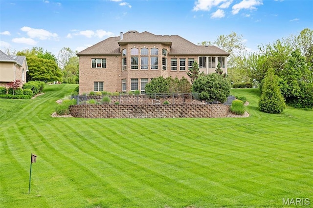rear view of property with a lawn and brick siding