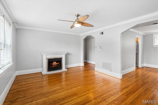 7570 Byron Pl Unit 3W, Saint Louis, MO 63105 - unfurnished living room featuring arched walkways, wood finished floors, a ceiling fan, a warm lit fireplace, and ornamental molding