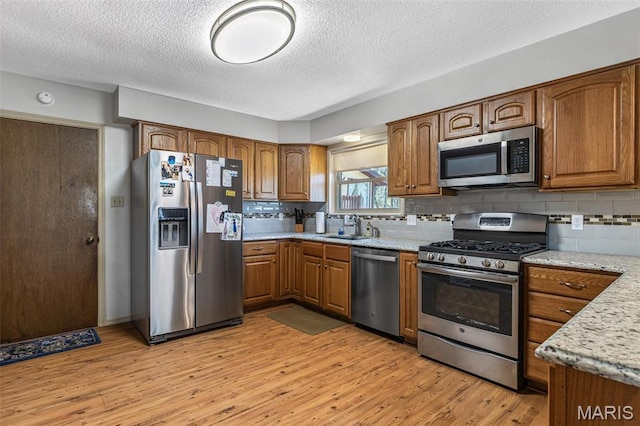13145 Wanda Lee Ln, Saint Genevieve, MO 63670 - kitchen with appliances with stainless steel finishes, a sink, brown cabinetry, a textured ceiling, and decorative backsplash