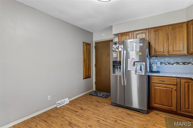 13145 Wanda Lee Ln, Saint Genevieve, MO 63670 - kitchen with stainless steel refrigerator with ice dispenser, light wood finished floors, brown cabinetry, and a textured ceiling
