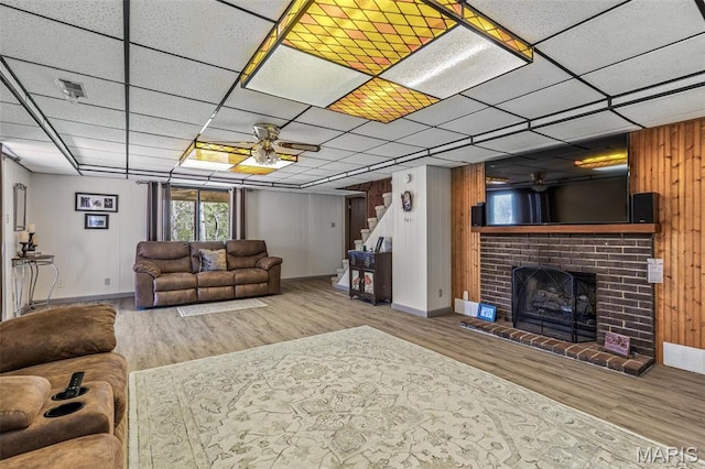 13145 Wanda Lee Ln, Saint Genevieve, MO 63670 - living room with ceiling fan, wood finished floors, stairs, a brick fireplace, and wooden walls
