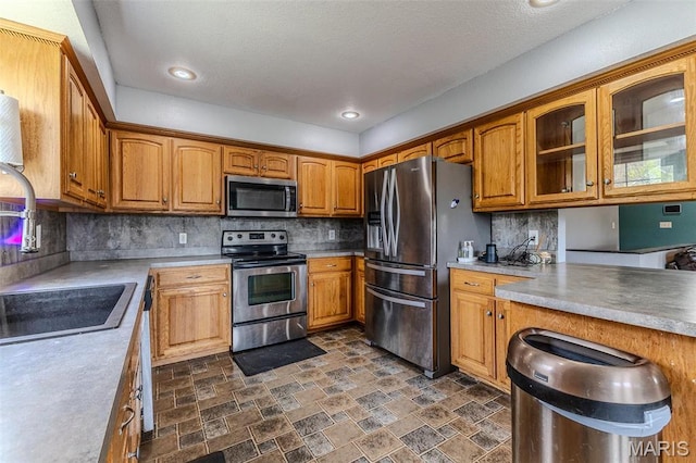 20373 Heritage Rd, Saint Robert, MO 65584 - kitchen with stainless steel appliances, brown cabinetry, glass insert cabinets, stone finish flooring, and a sink