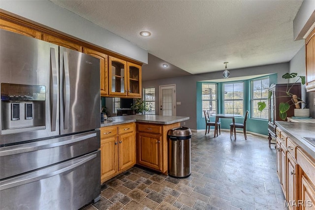 20373 Heritage Rd, Saint Robert, MO 65584 - kitchen with stainless steel fridge, a peninsula, brown cabinetry, glass insert cabinets, and a textured ceiling