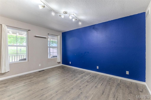 20373 Heritage Rd, Saint Robert, MO 65584 - spare room featuring wood finished floors, a textured ceiling, rail lighting, and baseboards