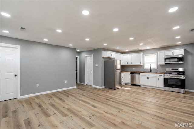 kitchen with appliances with stainless steel finishes, a sink, baseboards, light wood-style flooring, and recessed lighting