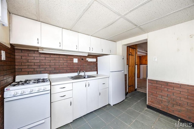 10 Hill Dr, Fairview Heights, IL 62208 - kitchen with white appliances, a paneled ceiling, a sink, light countertops, and dark tile patterned flooring