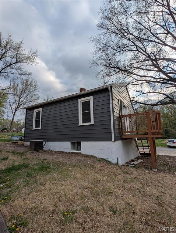 view of side of home featuring a chimney, a lawn, and a wooden deck