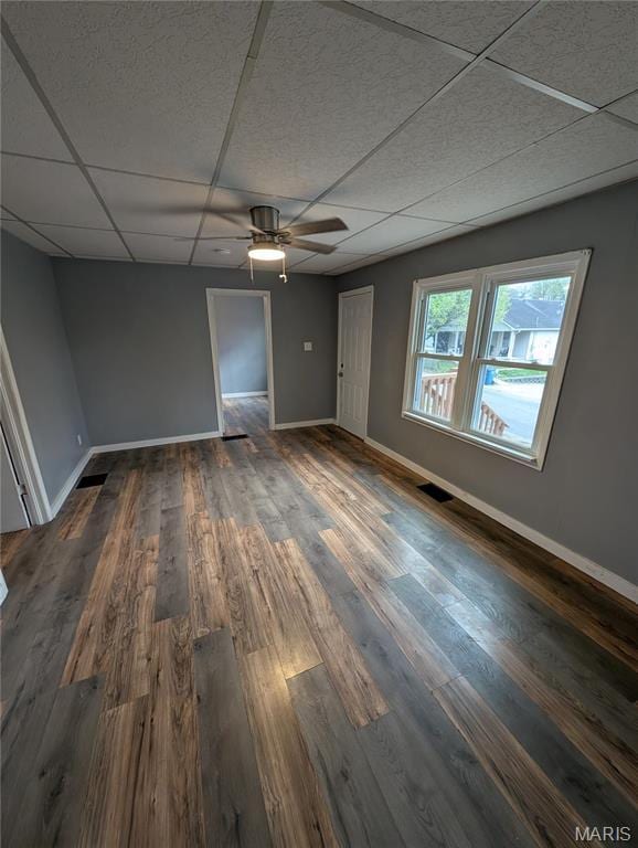 spare room with a paneled ceiling, baseboards, dark wood-style floors, and a ceiling fan