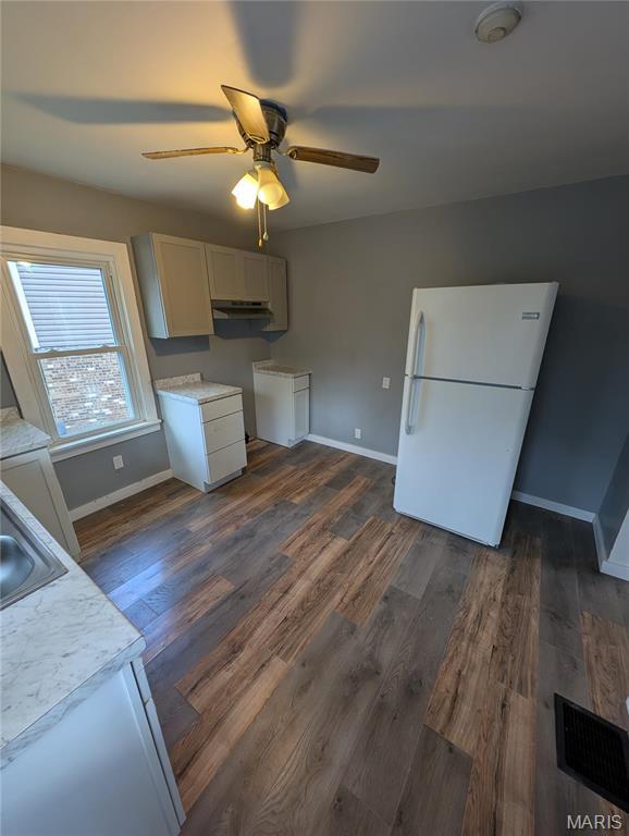 kitchen with freestanding refrigerator, baseboards, light countertops, a ceiling fan, and dark wood-type flooring