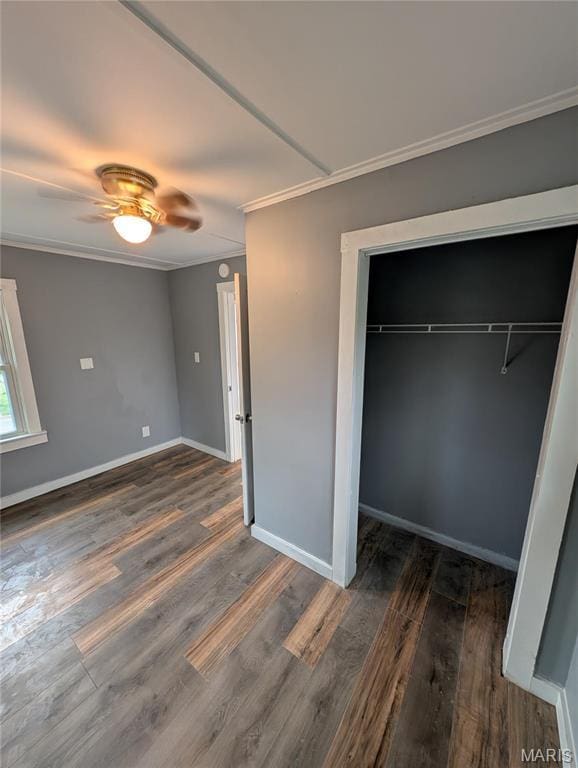 unfurnished bedroom with ornamental molding, wood finished floors, a closet, baseboards, and ceiling fan