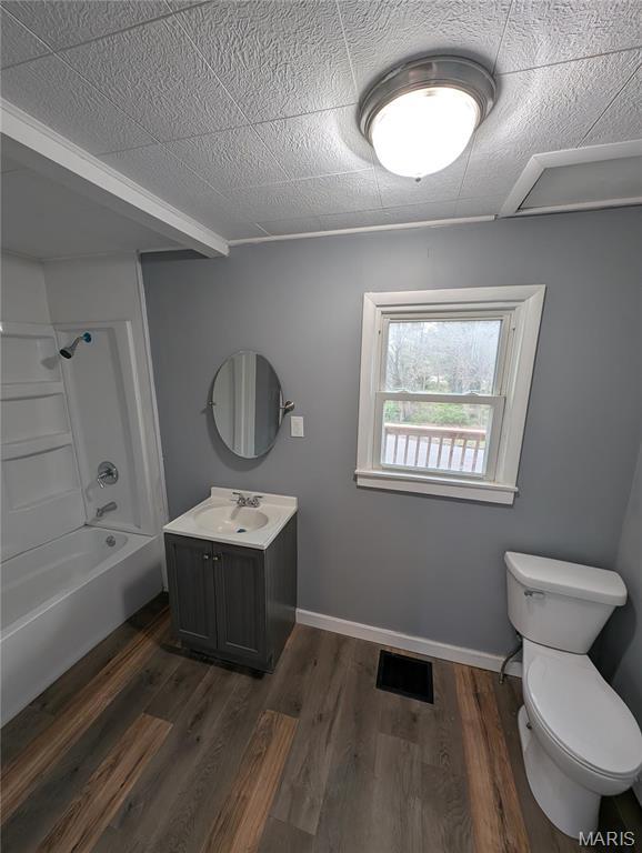 bathroom with toilet, shower / bath combination, vanity, and wood finished floors