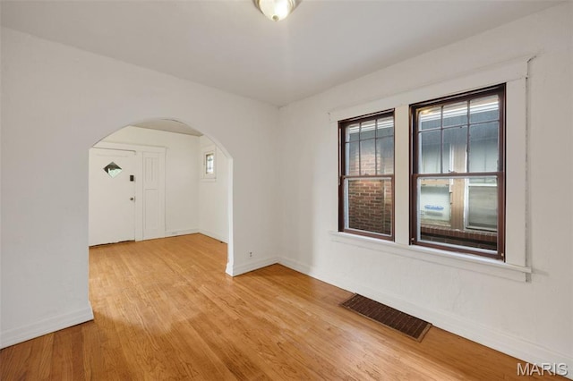 5923 Sherry Ave, Saint Louis, MO 63136 - spare room featuring arched walkways, plenty of natural light, baseboards, and light wood-style flooring