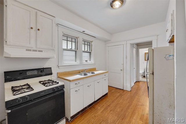 5923 Sherry Ave, Saint Louis, MO 63136 - kitchen featuring gas range oven, freestanding refrigerator, ventilation hood, white cabinets, and light wood-style flooring