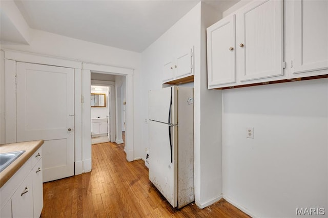 5923 Sherry Ave, Saint Louis, MO 63136 - kitchen featuring freestanding refrigerator, white cabinets, light wood finished floors, and light countertops
