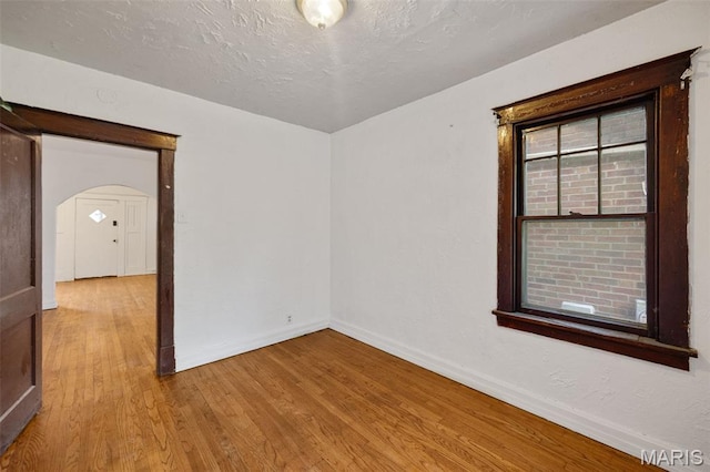 5923 Sherry Ave, Saint Louis, MO 63136 - empty room featuring baseboards, wood finished floors, arched walkways, and a textured ceiling