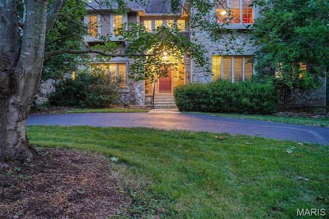 view of front facade with stone siding, a front lawn, and entry steps