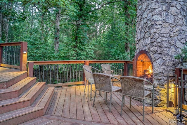 wooden terrace featuring an outdoor stone fireplace