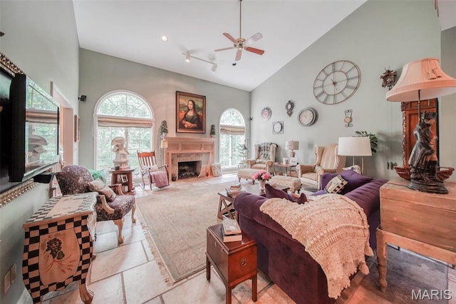 living room featuring high vaulted ceiling, ceiling fan, plenty of natural light, and a high end fireplace