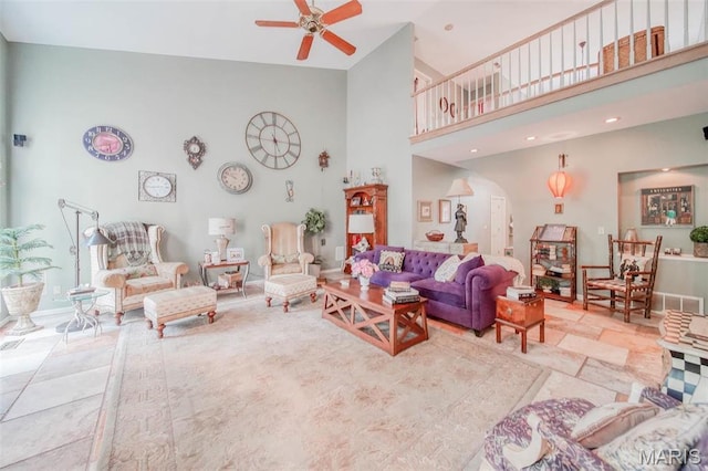 living area with a high ceiling, a ceiling fan, and arched walkways