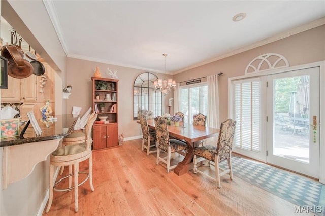 dining area with light wood-style floors, a chandelier, crown molding, and baseboards
