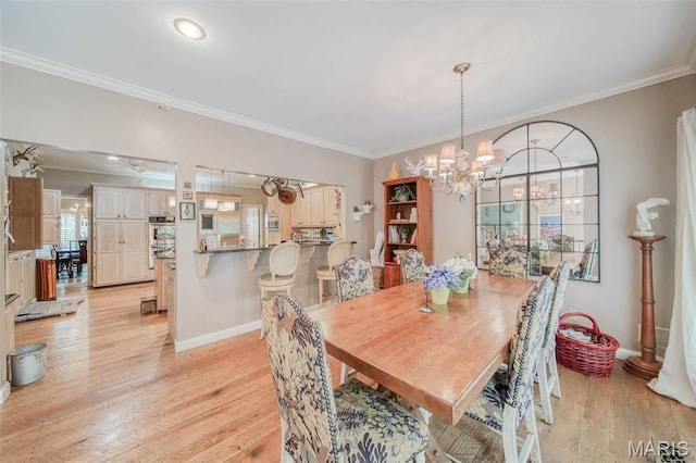 dining area featuring ornamental molding, a chandelier, light wood finished floors, and baseboards