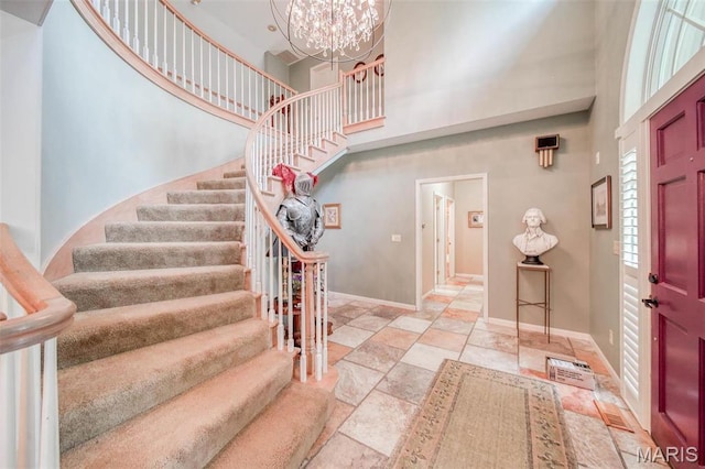 foyer with a high ceiling, stairs, stone tile floors, baseboards, and a chandelier