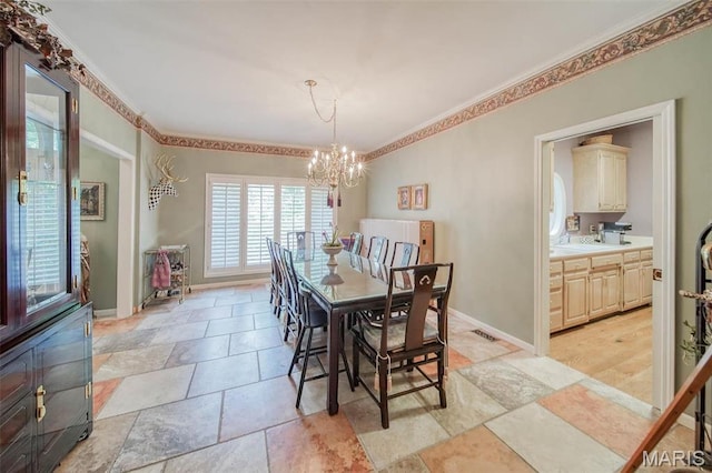 dining room with a chandelier, ornamental molding, light stone finish floors, and baseboards